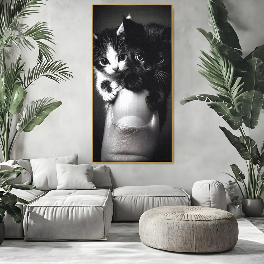 Tablou canvas cu tablou canvas cu doi pisoi mici agatati de un deget, in rama de aluminiu auriu, pe perete intr-un living